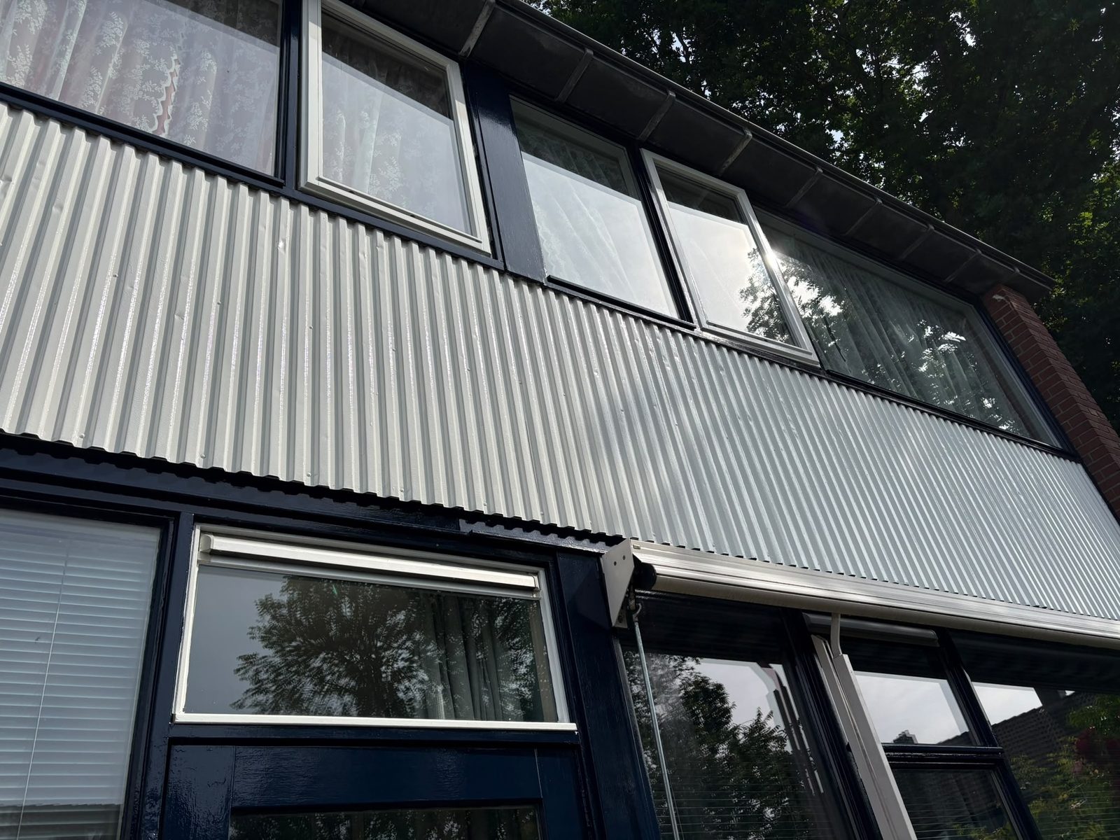 Detail van gevelbekleding en kozijnen zwart geschilderd